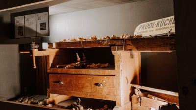 Alte Werkbank mit Holzspänen, rechts darauf Schild mit der Aufschrift "Prödl-Küchen"
