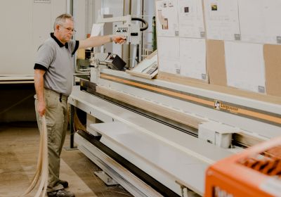 Mann schneidet Parkettbretter mit Sägemaschine.