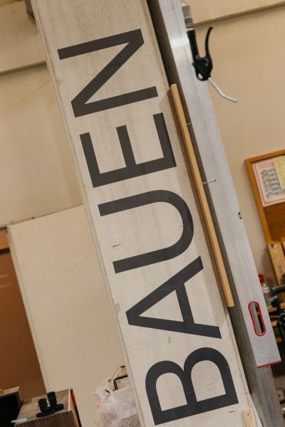 Brett mit schrägem Schriftzug von recht unten nach links oben: BAUEN
