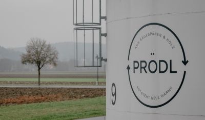 Prödl-Logo im Vordergrund, dahinter Felder und ein kahler Baum