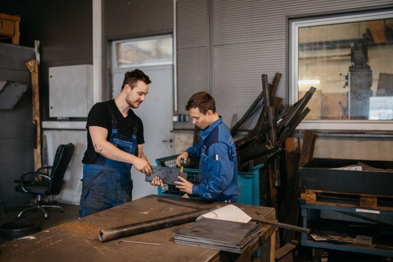 © Christine Wiener Arbeiter messen gemeinsam ein Metallstück.