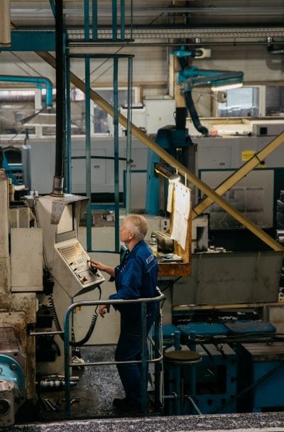 Arbeiter bedient Maschine über Konsole.