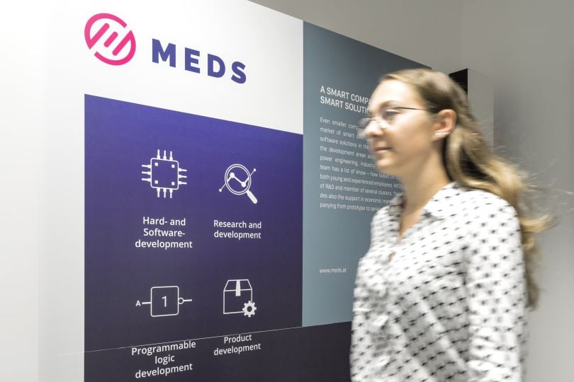 Frau geht an MEDS-Firmenschild vorbei