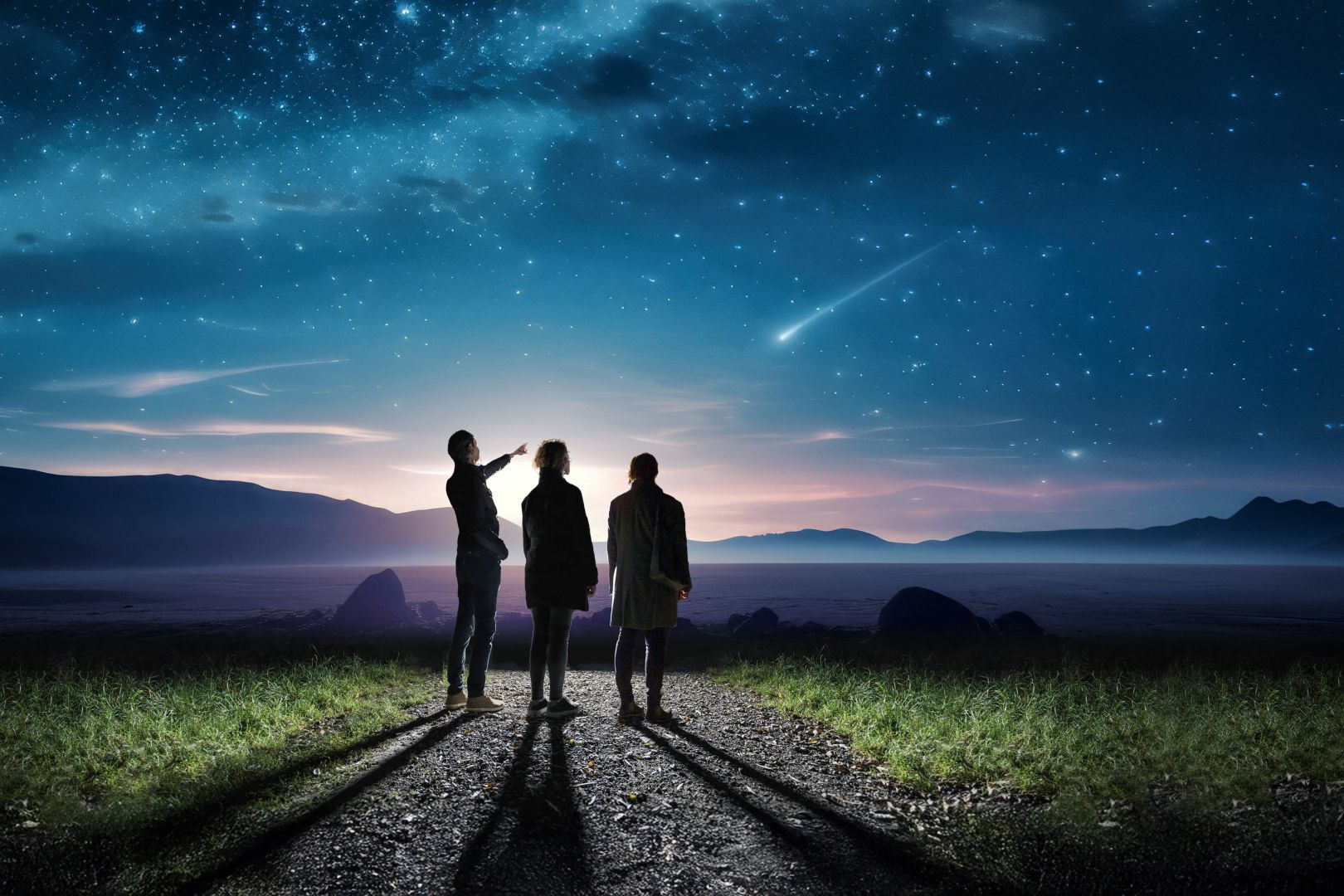 Familie steht in der Nacht auf Weg und beobachtet eine Sternschnuppe