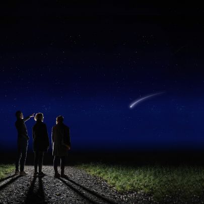 Familie steht in der Nacht auf Weg und beobachtet eine Sternschnuppe