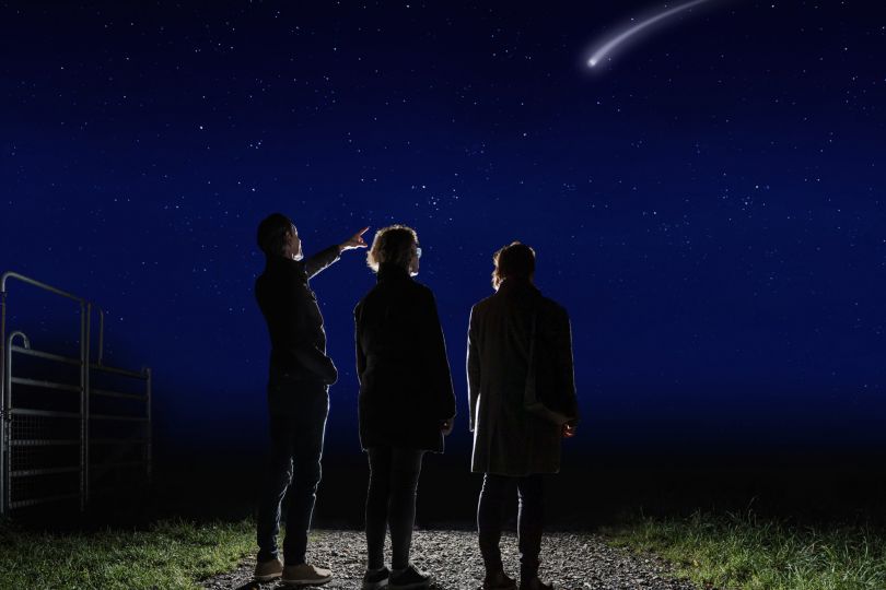 © Niki Schreinlechner Familie steht in der Nacht auf Weg und beobachtet eine Sternschnuppe