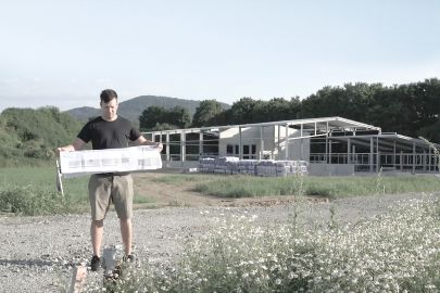 Mann steht mit Plan vor Rohbau