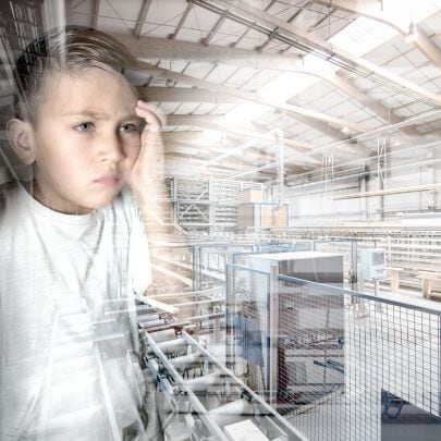 Ein Junge schaut durch eine Glasscheibe auf eine Fabrikshalle.