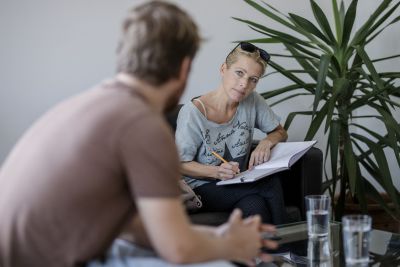 Sigrid Gaisch-Faustmann sitzt in Interviewsituation und schreibt in Block.