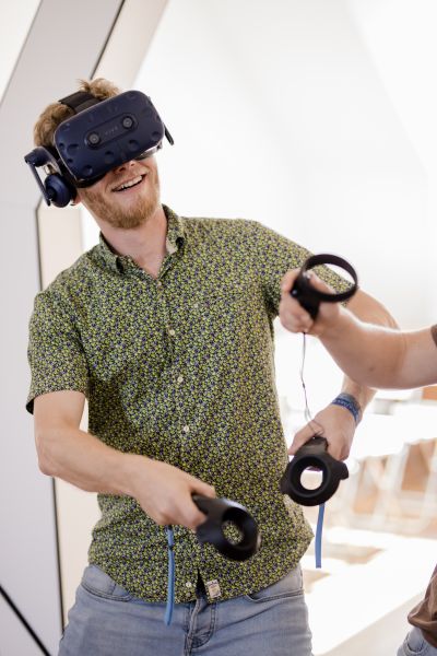 Mann mit Virtual-Reality-Brille und Joysticks in den Händen.