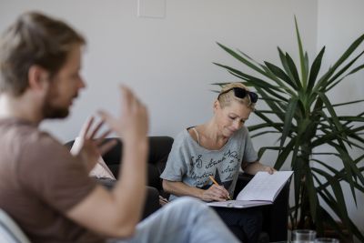 Sigrid Gaisch-Faustmann sitzt in Interviewsituation und schreibt in Block.