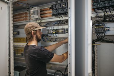 Junger Mann mit Kappe arbeitet an Schaltkreisen