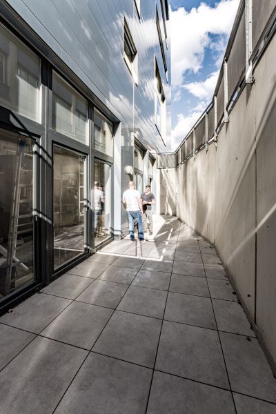Terrasse von modernem Gebäude, zwei Männer unterhalten sich an Stehtisch