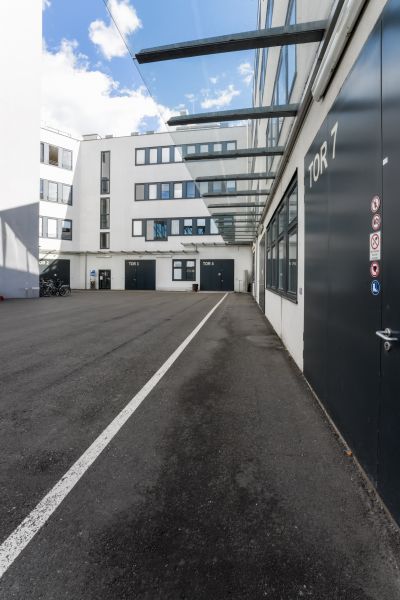 Modernes Gebäude in weiß, nummerierte Tore, Asphalt im Vordergrund