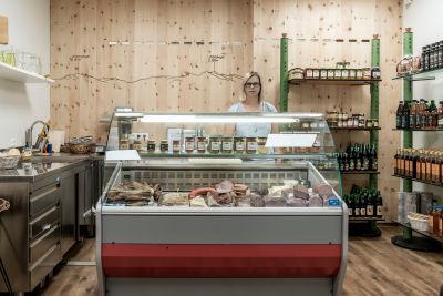 Frau steht hinter Wursttheke