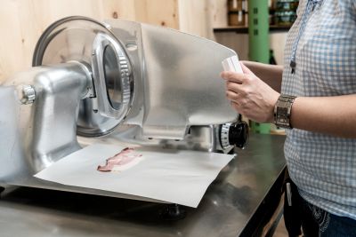 Schinken wird mit Wurstschneidemaschine aufgeschnitten