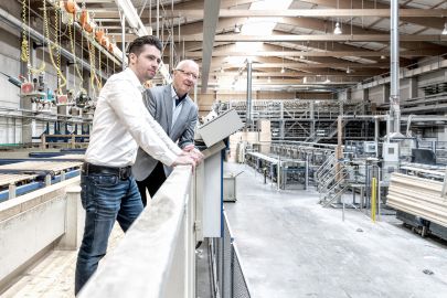 Älterer und jüngerer Mann schauen auf Prduktionshalle