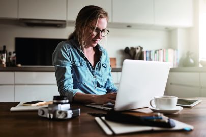 © Kopfstand Frau arbeitet in Küche am Laptop