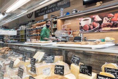 Verkäuferin in Bioladen, Käse im Vordergrund