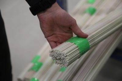 Hand hält Halbzeug in Bündeln mit grünem Tape umwickelt