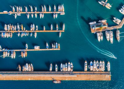 Aerial view of amazing boats at sunset. Minimalistic landscape with boats and sea in marina bay. Top view from drone of harbor with yacht, motorboat and sailboat. Beautiful port