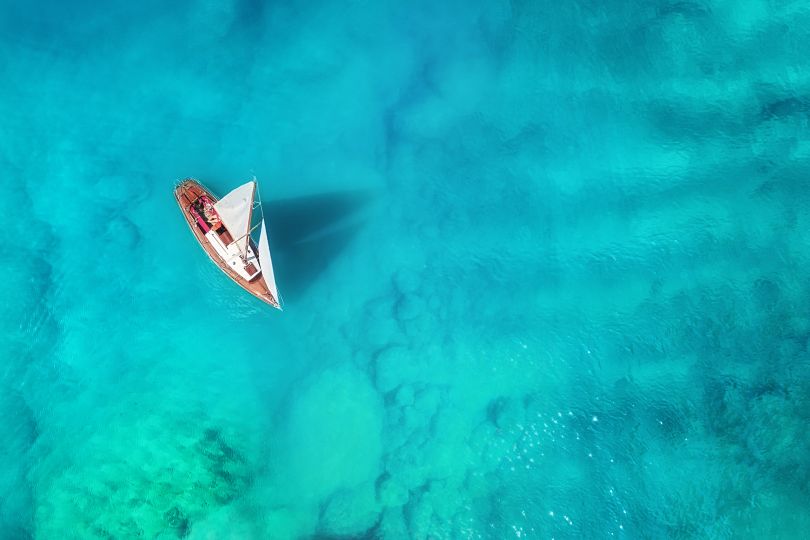 Yacht on the sea from top view. Turquoise water background from top view. Summer seascape from air. Travel concept and idea