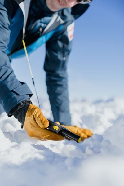 Mann im Schnee mit Lawinenverschüttetenmessgerät