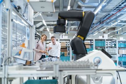(c) Westend61_Daniel_Ingold Businessman and businesswoman talking in a modern factory hall