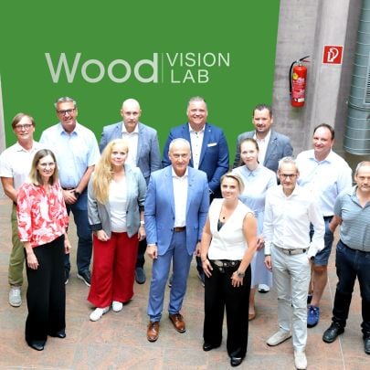 Menschengruppe vor grüner Tafel "Wood Vision Lab"